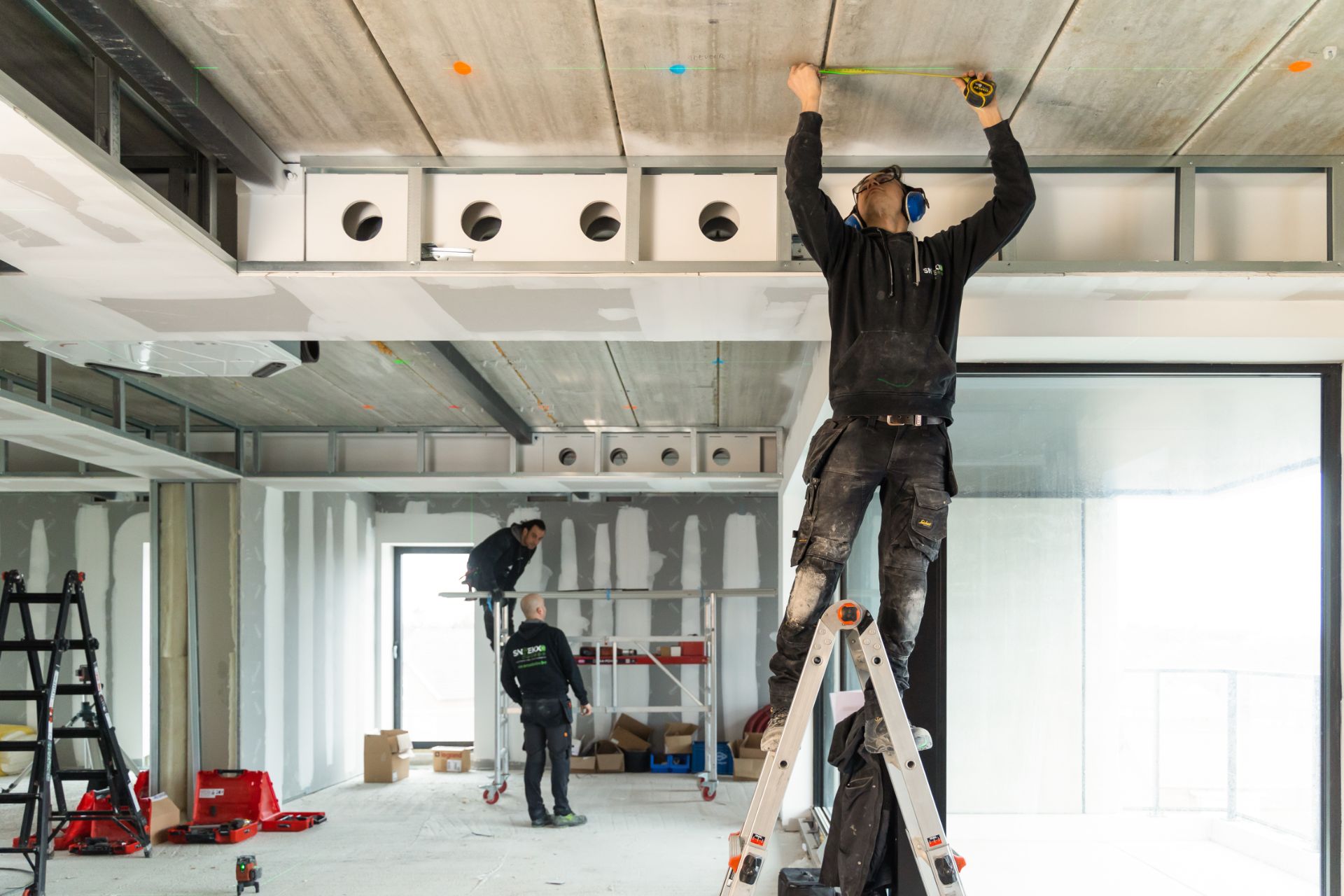 Werknemer Snoekx draag zonnepaneel omhoog via ladder